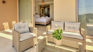 Een moderne hotelkamer met een balkon, rieten meubilair, een bed en een groot raam.
