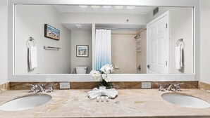 A bathroom with a large mirror, two sinks, a shower, and a toilet. - Gulfside 1302 - Gulf Front! Community Pool! Hot Tub! Fitness Center! Tennis! (Miramar Beach)