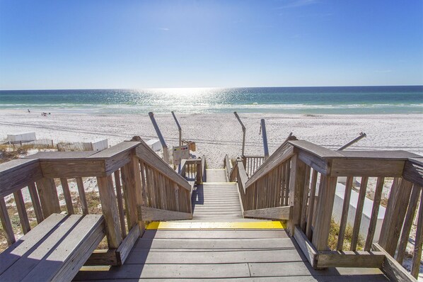 A wooden staircase leading to a beach with a clear view of the ocean.