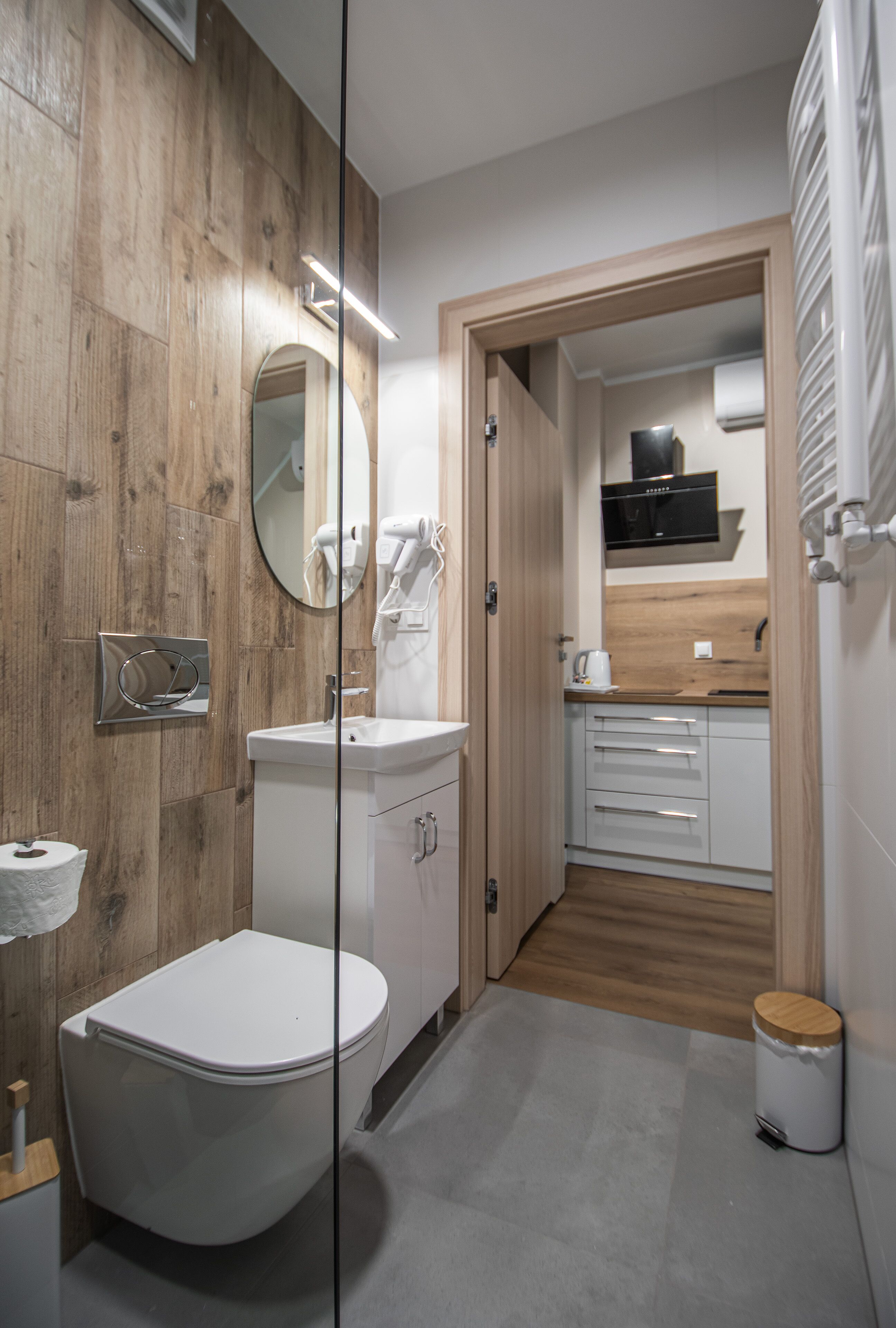 Une salle de bain moderne avec un meuble-lavabo en bois, des toilettes blanches et un espace lavabo séparé.