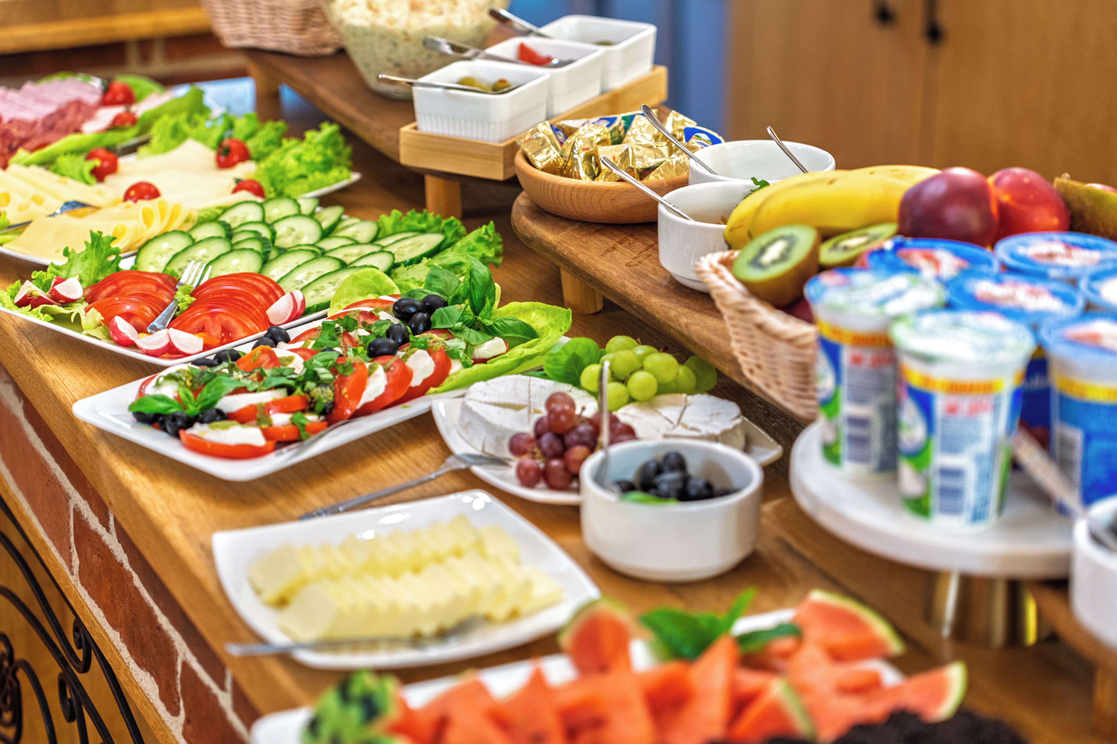 Un buffet con diversi cibi, tra cui insalate, frutta, formaggi e yogurt.
