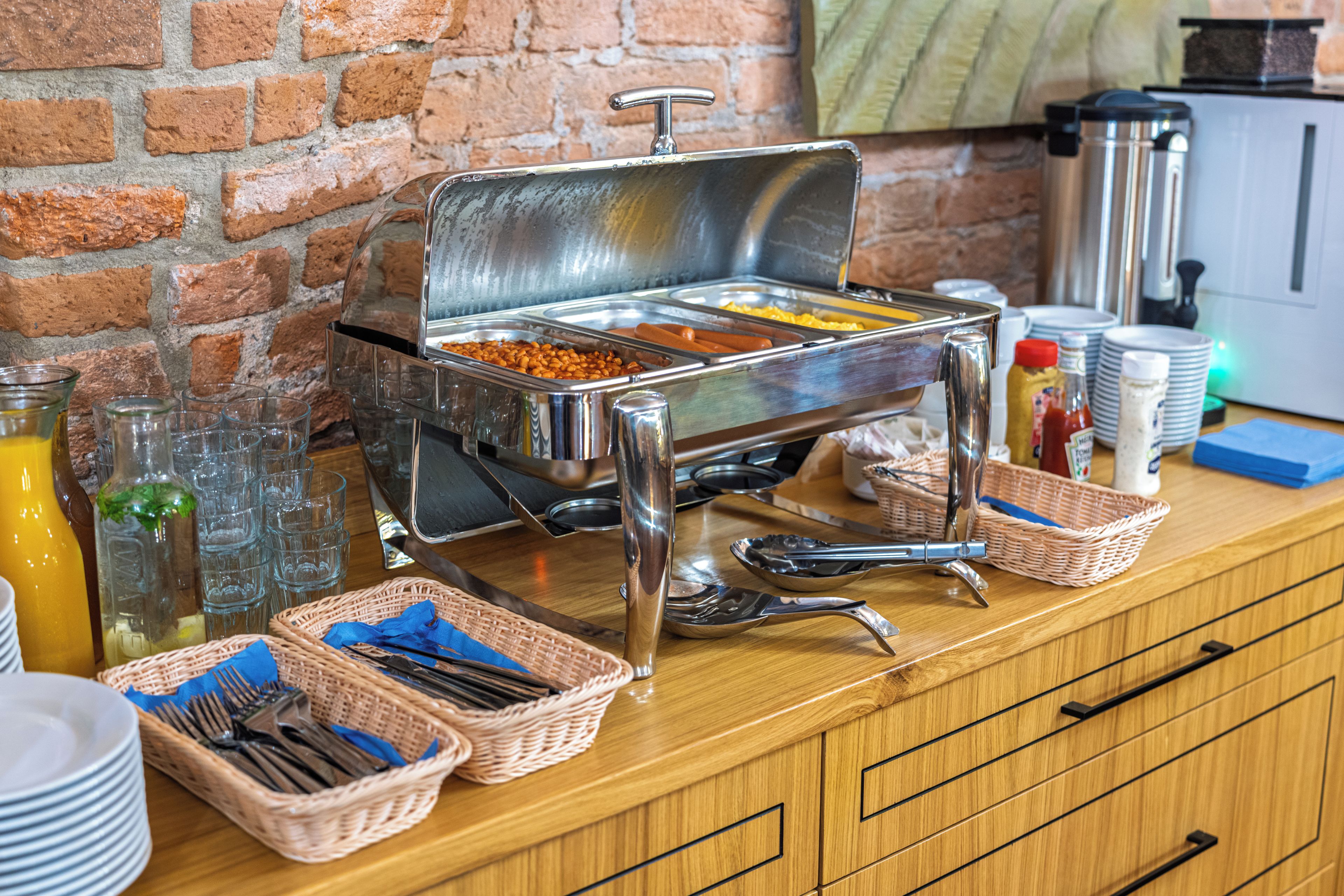 A buffet setup with various food items, serving utensils, and condiment bottles.