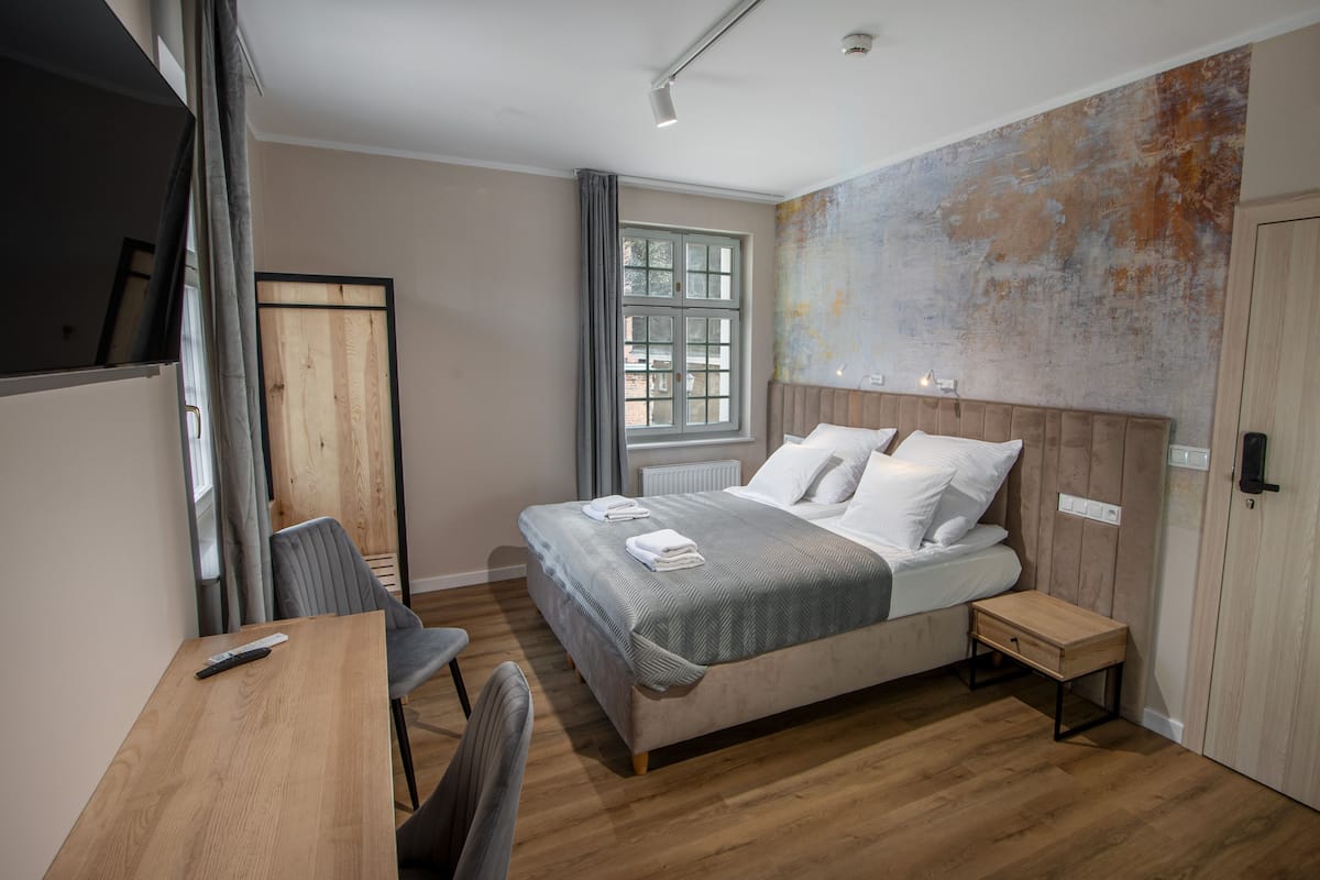 Een moderne slaapkamer met een houten bed, een bureau en een stoel.