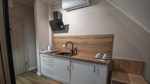 Une cuisine compacte dotée d’un plan de travail en bois, d’un évier et d’une hotte intégrée.