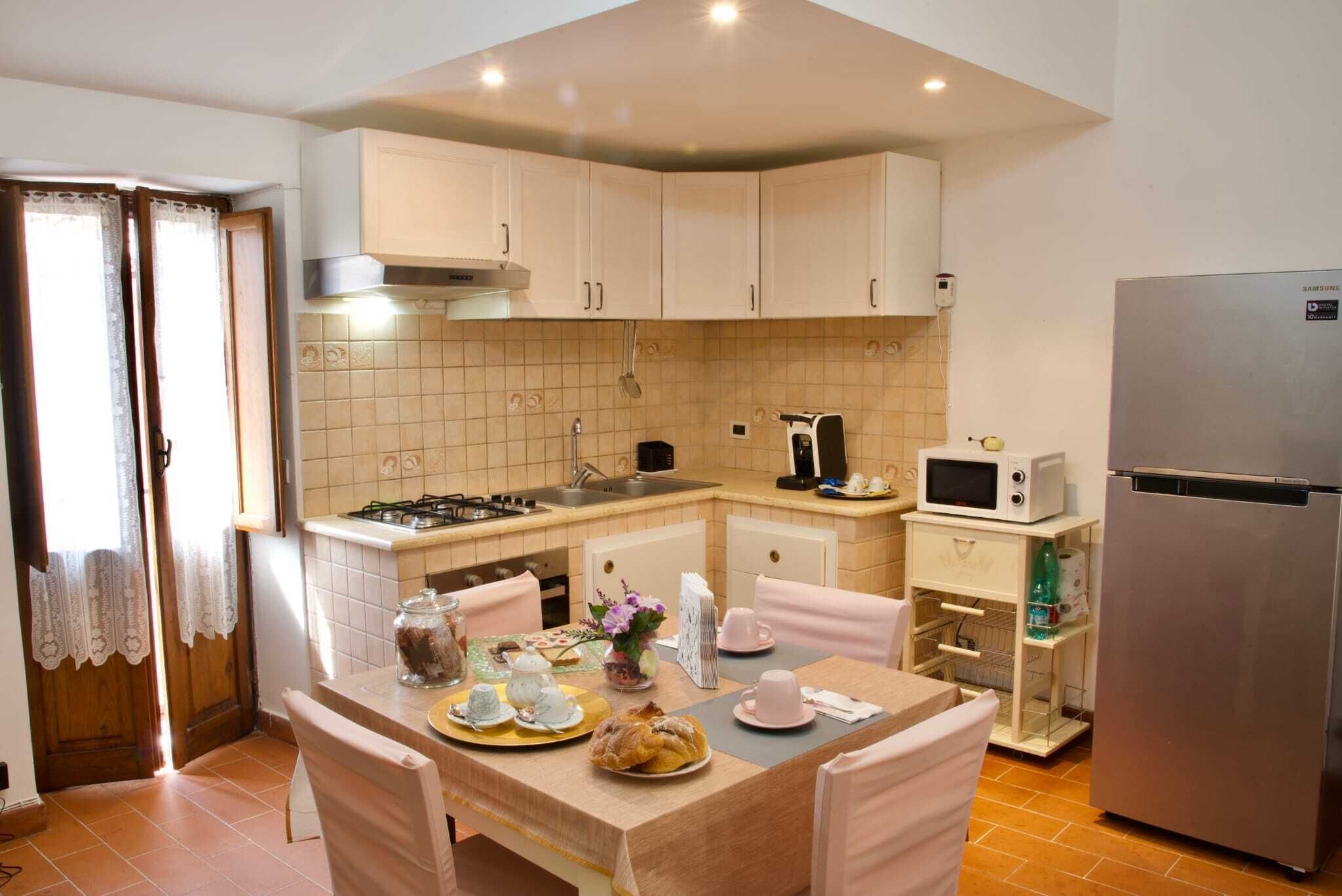 A compact kitchen with white cabinets, a stainless steel refrigerator, a microwave, and a gas stove.