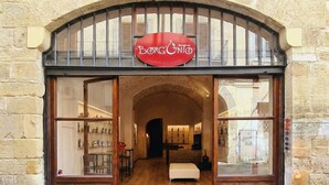 Une devanture de magasin avec une façade en pierre, de grandes portes en bois et une enseigne au-dessus de l’entrée.