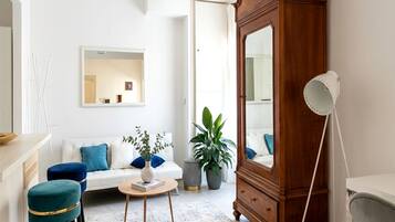 A living room with a white sofa, a wooden cabinet, a round coffee table, and a potted plant.