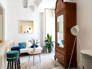 A living room with a white sofa, a wooden cabinet, a round coffee table, and a potted plant.