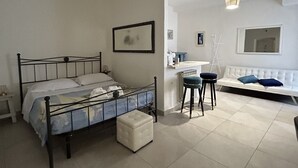 Ein Schlafzimmer mit einem Bett, einem kleinen Tisch, einer Bank und einem Sofa.