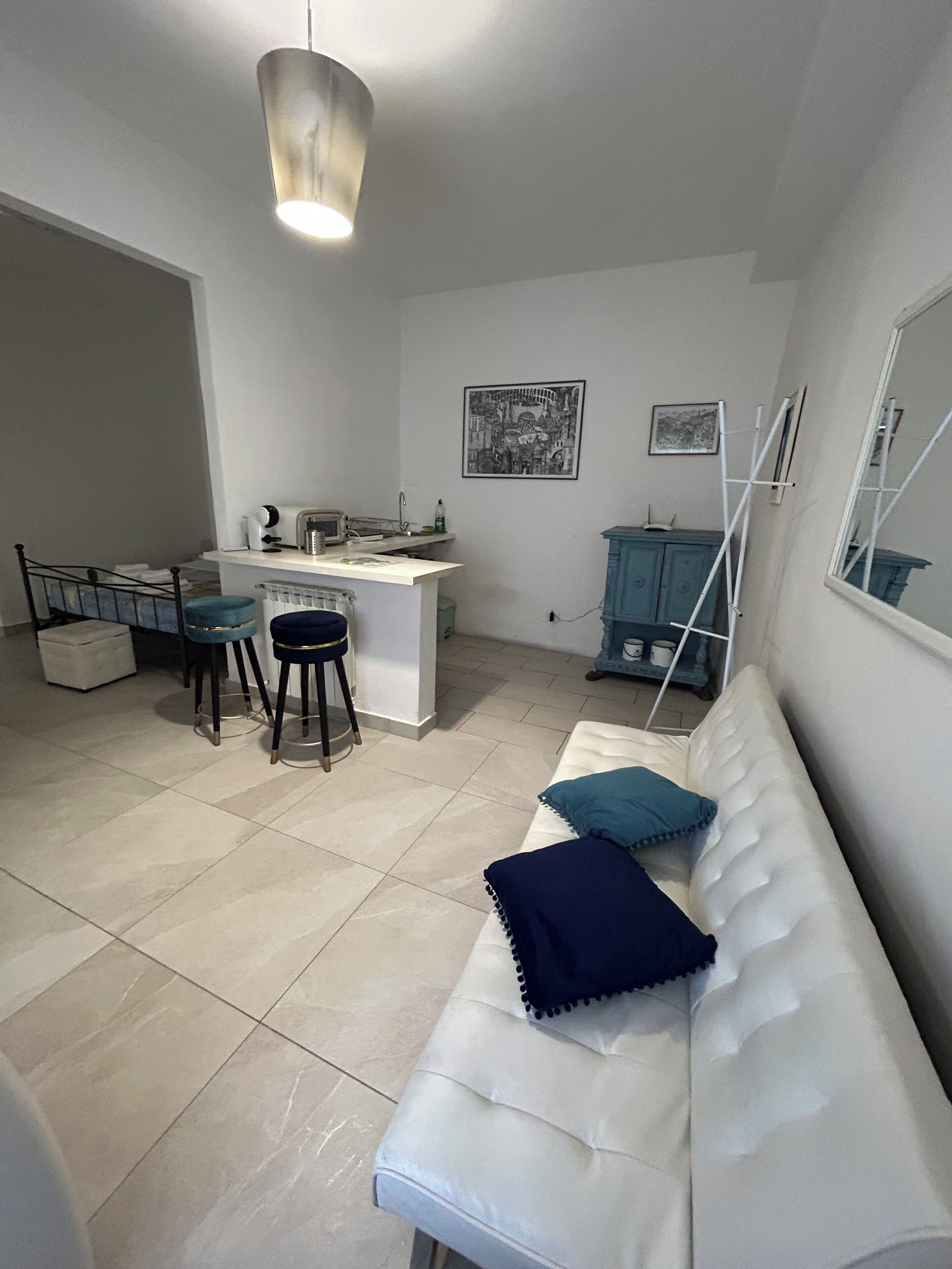 A modern living room with a sofa, a small kitchen area, and a dining space.