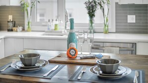 Eine moderne Küche mit einem Holztisch, gedeckt für eine Mahlzeit, mit einer Weinflasche, Gläsern und verschiedenen Besteck.