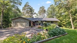 Een gelijkvloers huis met garage, omgeven door een verzorgd gazon en bomen.