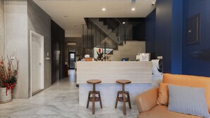 A modern interior with a kitchen area, a bar counter with stools, and a sofa with a patterned pillow. - Deep blue 23 B&B (Magong)