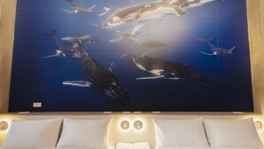 A hotel room with a large whale mural on the wall, a bed with white linens, and two bedside lamps. - Deep blue 23 B&B (Magong)