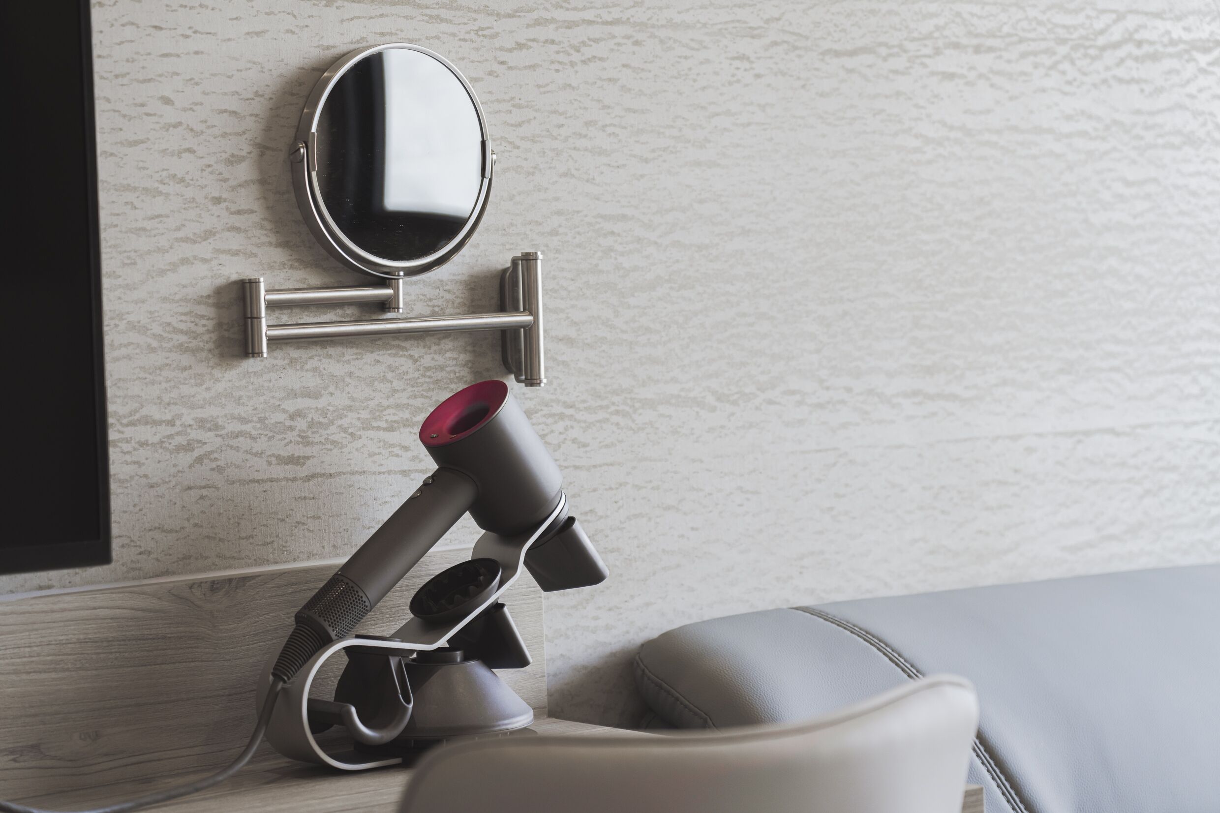Een moderne badkamer met een handdoekrek, een spiegel en een haardroger.