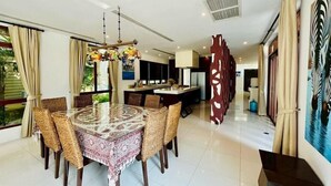 A spacious dining area with a round table, wicker chairs, and a decorative centerpiece. - Amatapura Beach Villa 12 (Krabi)