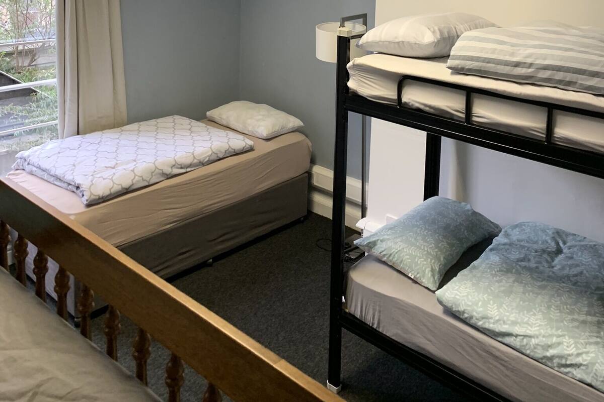 Une chambre de dortoir avec des lits superposés, une fenêtre avec des rideaux et une table de chevet avec une lampe.