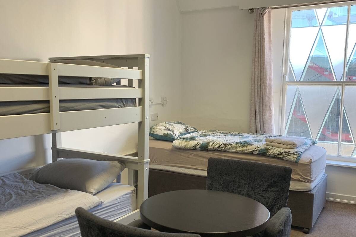 Une chambre de type dortoir, avec des lits superposés, une table ronde et des chaises.