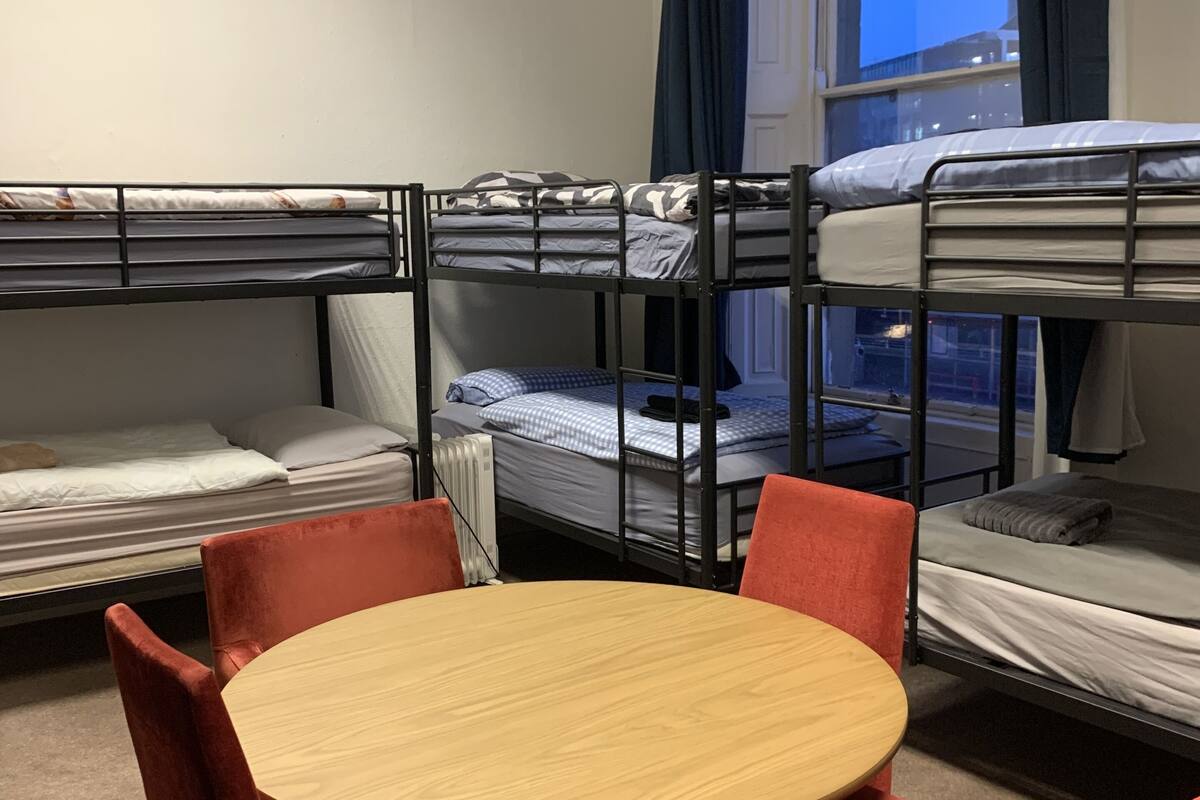 Une chambre avec trois lits superposés, une table ronde et des chaises rouges.