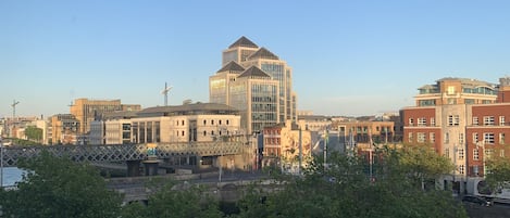 A cityscape with modern buildings, a bridge, and a green bus on the street.