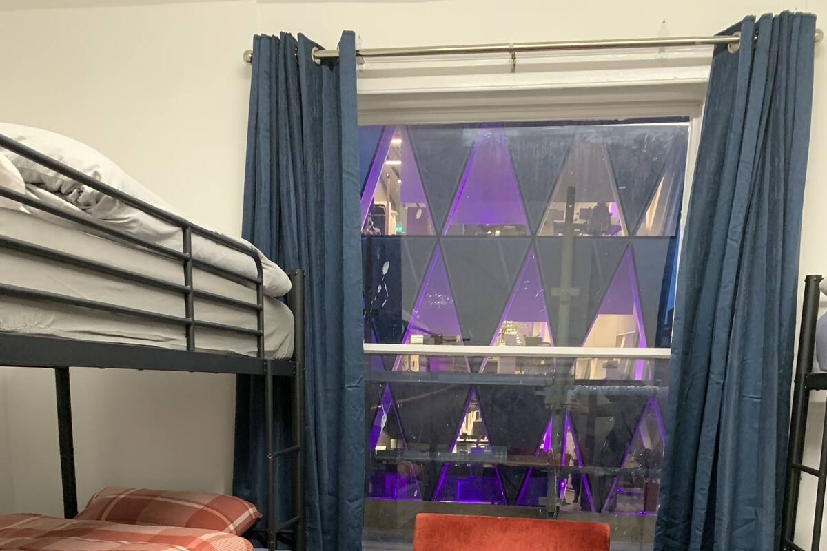 Une chambre de dortoir avec des lits superposés, une table en verre et des chaises orange.