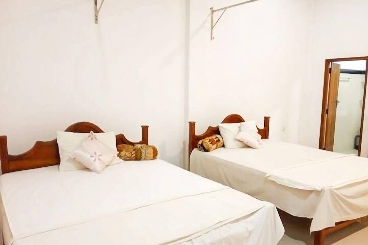 Two single beds with wooden headboards and white bedding in a room with white walls.