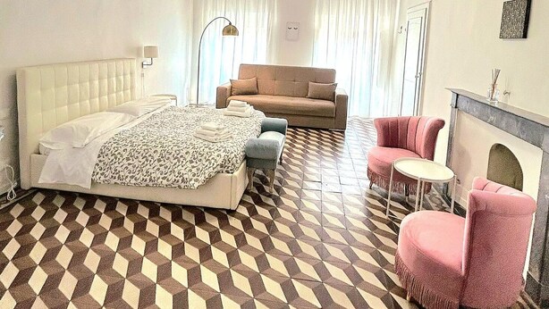 A bedroom with a bed, a sofa, a small table, and a fireplace. - Loft with private bathroom (Arezzo)