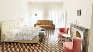 A hotel room with a checkered floor, a bed, a sofa, a chair, and a fireplace. - Loft with private bathroom (Arezzo)