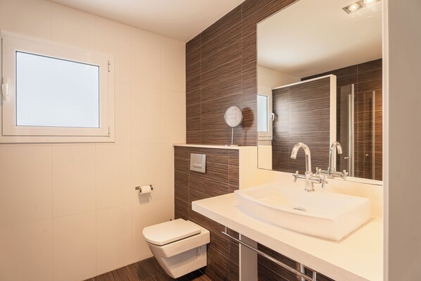 A modern bathroom with a white sink, a large mirror, and a toilet. - V196| Villa Brisas - Four Bedroom Villa, Sleeps 8 (Torre Soli Nou)