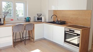 Een moderne keuken met witte kasten, een houten aanrecht, een spoelbak, een waterkoker, een magnetron en een inbouwoven.