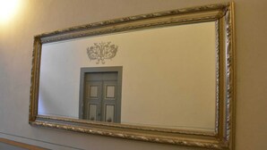 Ein Spiegel mit aufwendigem Goldrahmen, der an einer Wand befestigt ist.