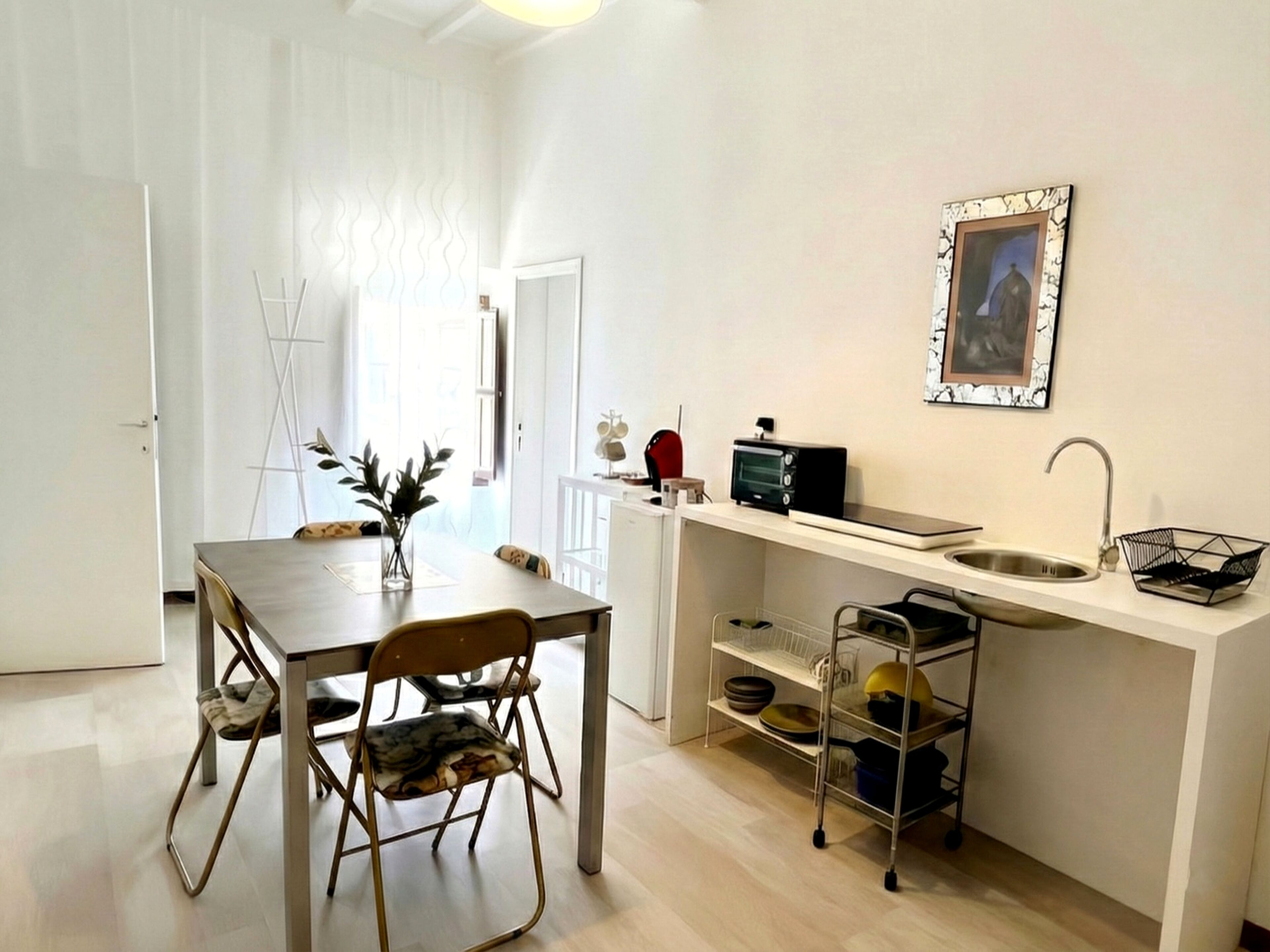 Une cuisine compacte comprenant une table à manger, des chaises, un grille-pain et un évier.