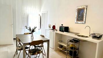 Une cuisine compacte comprenant une table à manger, des chaises, un grille-pain et un évier.