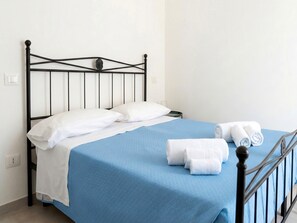 A single bed with a blue bedspread, white pillows, and two rolled towels on the side. - Penthouse in the heart of the city (Arezzo)