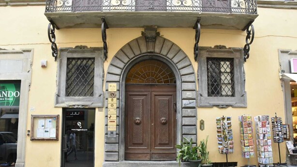 Ein Gebäude mit einer großen Zwerchstufe, zwei kleineren Fenstern und einem Balkon mit schmiedeeisernen Zierelementen.