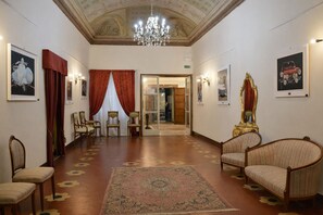 A spacious lobby with a patterned carpet, wooden chairs, a large ornate mirror, and artwork on the walls. - Penthouse in the heart of the city (Arezzo)