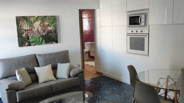 A living room with a grey sofa, a glass coffee table, and a painting of a leopard. - Ático en la Costa del sol a 15 Minutos de la Playa .en Tercera Planta sin Ascens (Arenas)