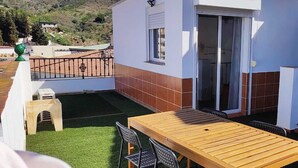 A patio with a wooden table and chairs, a small stool, and a green decorative item. - Ático en la Costa del sol a 15 Minutos de la Playa .en Tercera Planta sin Ascens (Arenas)