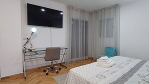 A hotel room with a bed, a desk with a chair, a TV, and a window with curtains. - Ático en la Costa del sol a 15 Minutos de la Playa .en Tercera Planta sin Ascens (Arenas)