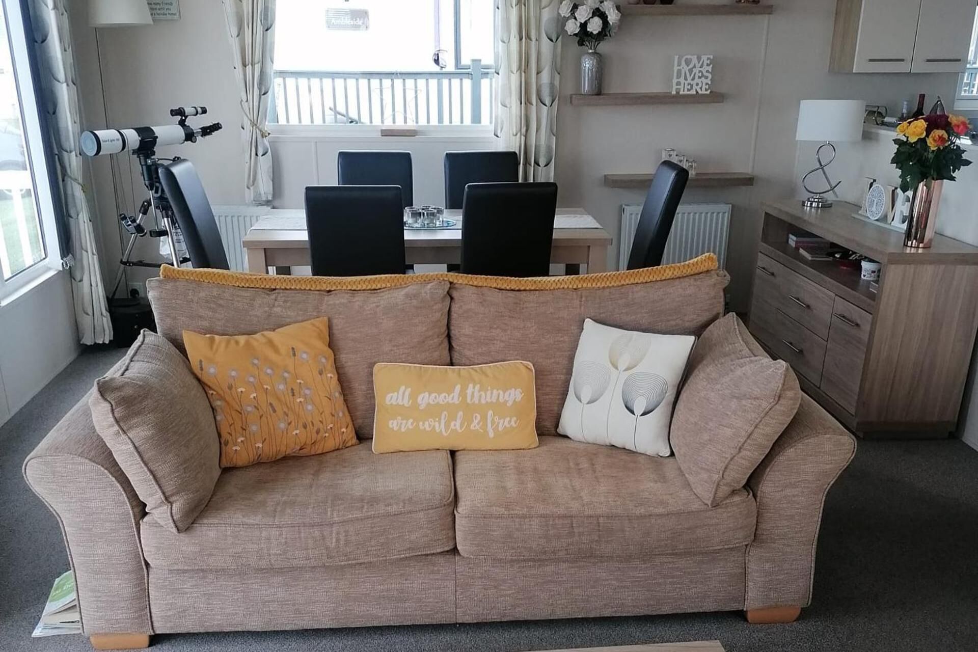 A living room with a beige sofa, a coffee table, and a dining area with a table and chairs.