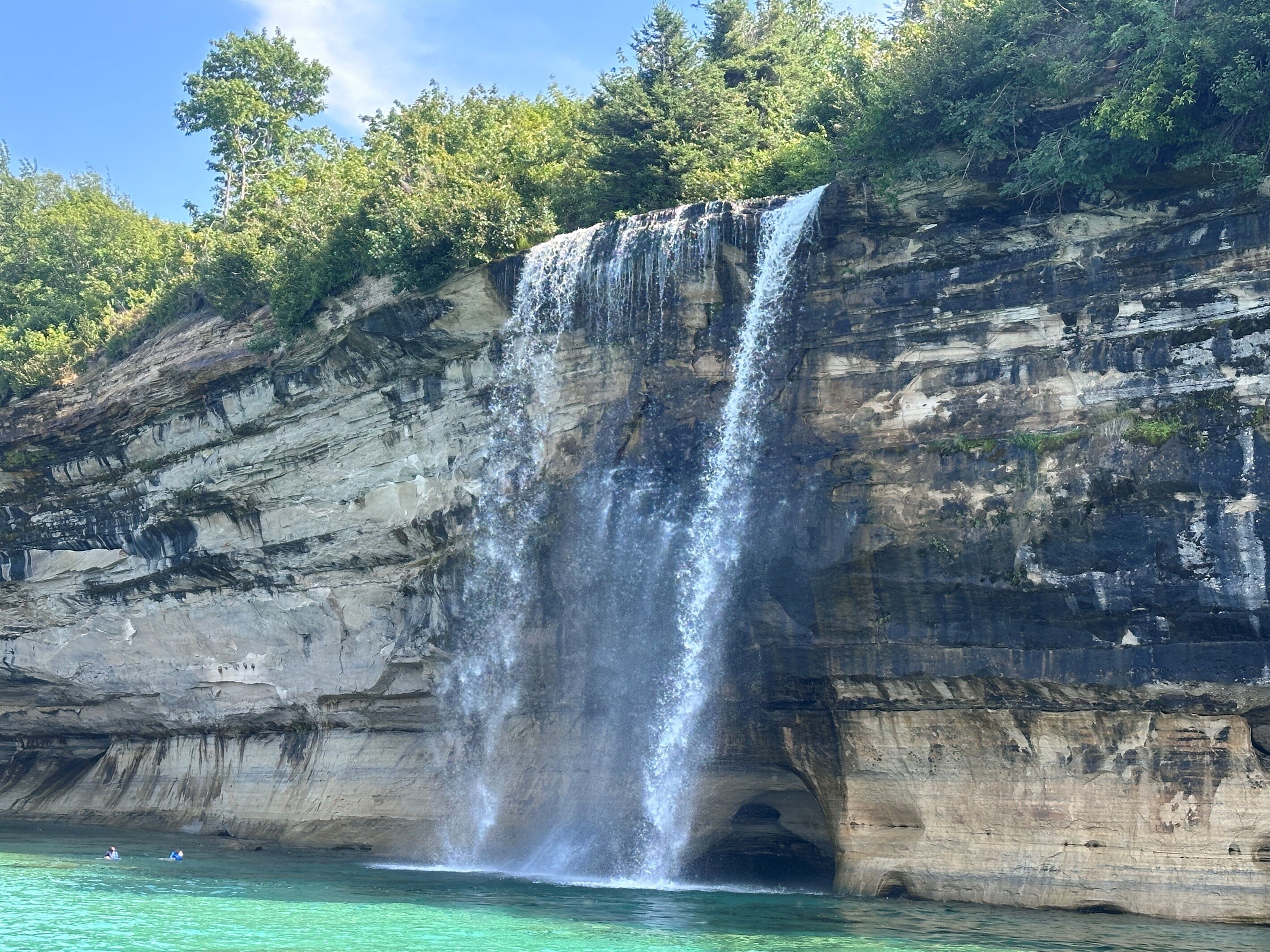 A waterfall cascading down a rocky cliff into a body of water.