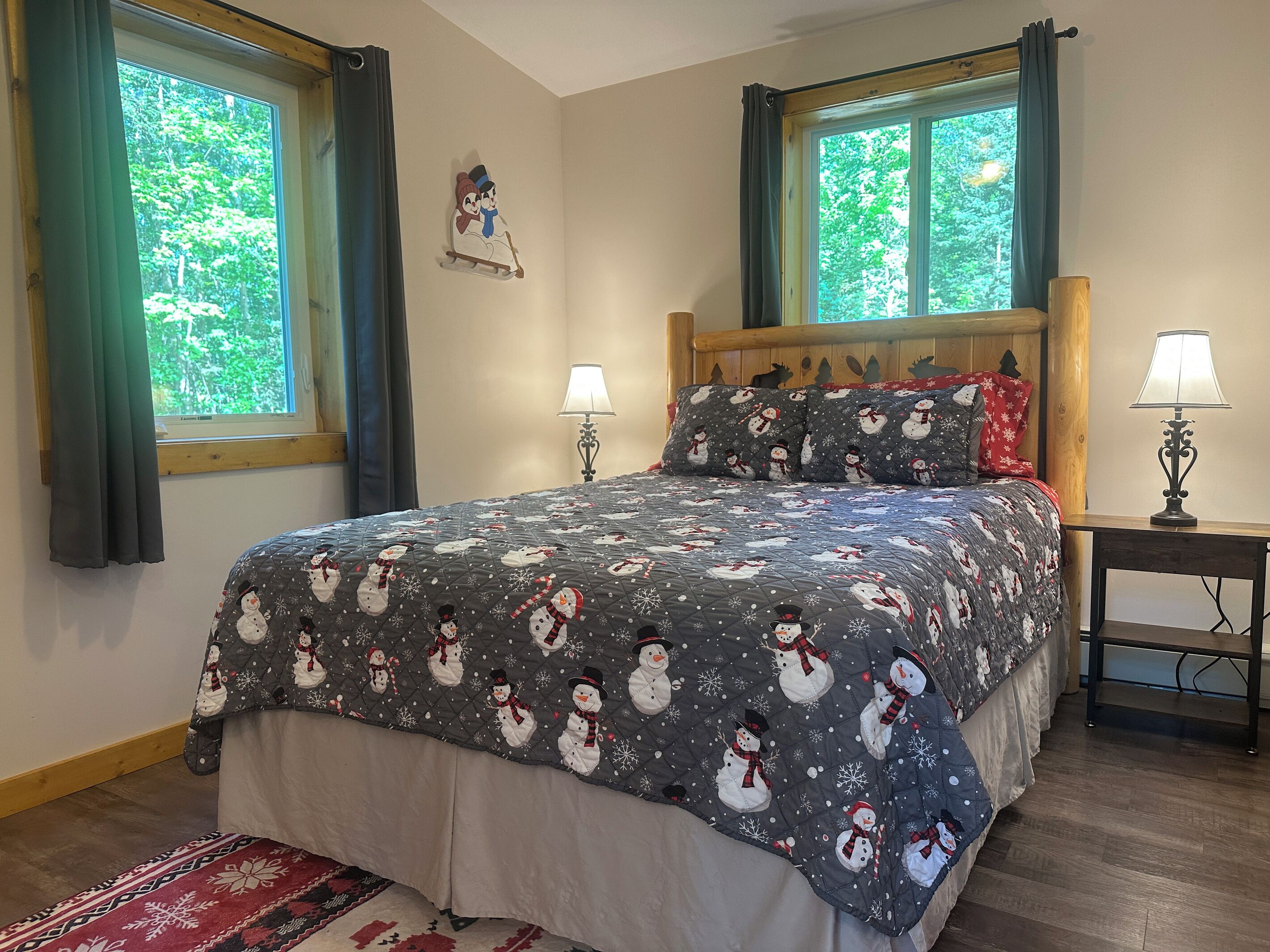 A bedroom with a bed, two bedside lamps, a window with curtains, and a wall decoration.