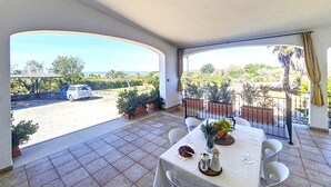 Een balkon met een eettafel, met uitzicht op een parkeerplaats en een mooi landschap.
