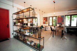 A modern interior with a red door, a multi-tiered glass and metal shelving unit, a dining area with a table and chairs, and large windows allowing natural light. - The Tbilisi Pod (Tbilisi)