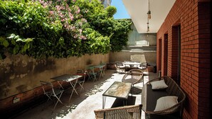 An outdoor patio with tables and chairs, a brick wall, and a hanging light fixture. - The Tbilisi Pod (Tbilisi)