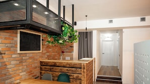 A cozy restaurant with a brick wall, wooden bench seating, and a hanging plant. - The Tbilisi Pod (Tbilisi)