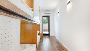 A narrow hallway with wooden flooring and white walls, leading to a door with a view of greenery outside. - The Tbilisi Pod (Tbilisi)