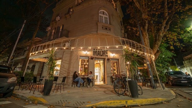 Un edificio con fachada curva, zona de estar al aire libre y un cartel que dice "MADRE".