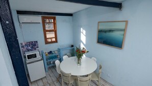 Una cocina compacta con una mesa blanca, sillas y un refrigerador pequeño.