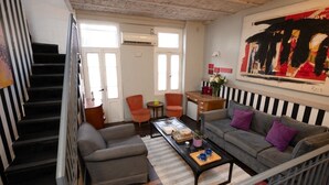 Una sala de estar con una escalera, un sofá, una mesa de centro y un cuadro en la pared.